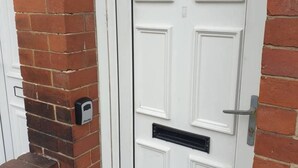 A white door with the number 1000 above it, a mail slot, and a doorbell. - South Shield's Emerald 2 Bed Apartment (South Shields)