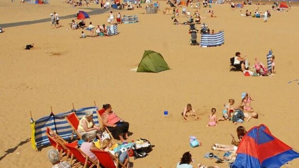 A beach with rows of beach chairs and umbrellas, a green tent, and people relaxing. - South Shield's Emerald 2 Bed Apartment (South Shields)