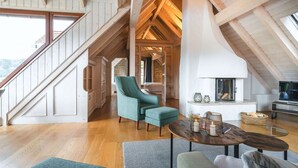 A spacious loft with a high ceiling, wooden beams, a staircase, a cozy seating area with a fireplace, and a view of the outdoors. - Ferienwohnungen Alte Destillerie Rathen (Rathen)