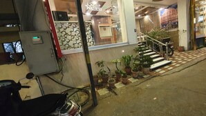 A hotel entrance with a staircase leading to the upper floor, potted plants, and a parked motorcycle. - Hotel Star Palace (Jaipur)