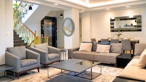 A modern living room with a sofa, armchairs, a coffee table, and a dining area with chairs and a table. - Taksim Elysium Residence CTS (Istanbul)