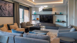 A modern living room with a large flat-screen TV, comfortable seating, and a decorative horse sculpture on the wall. - Taksim Elysium Residence CTS (Istanbul)