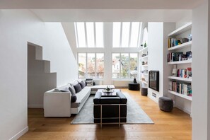 A modern living room with a sectional sofa, a coffee table, and a bookshelf.