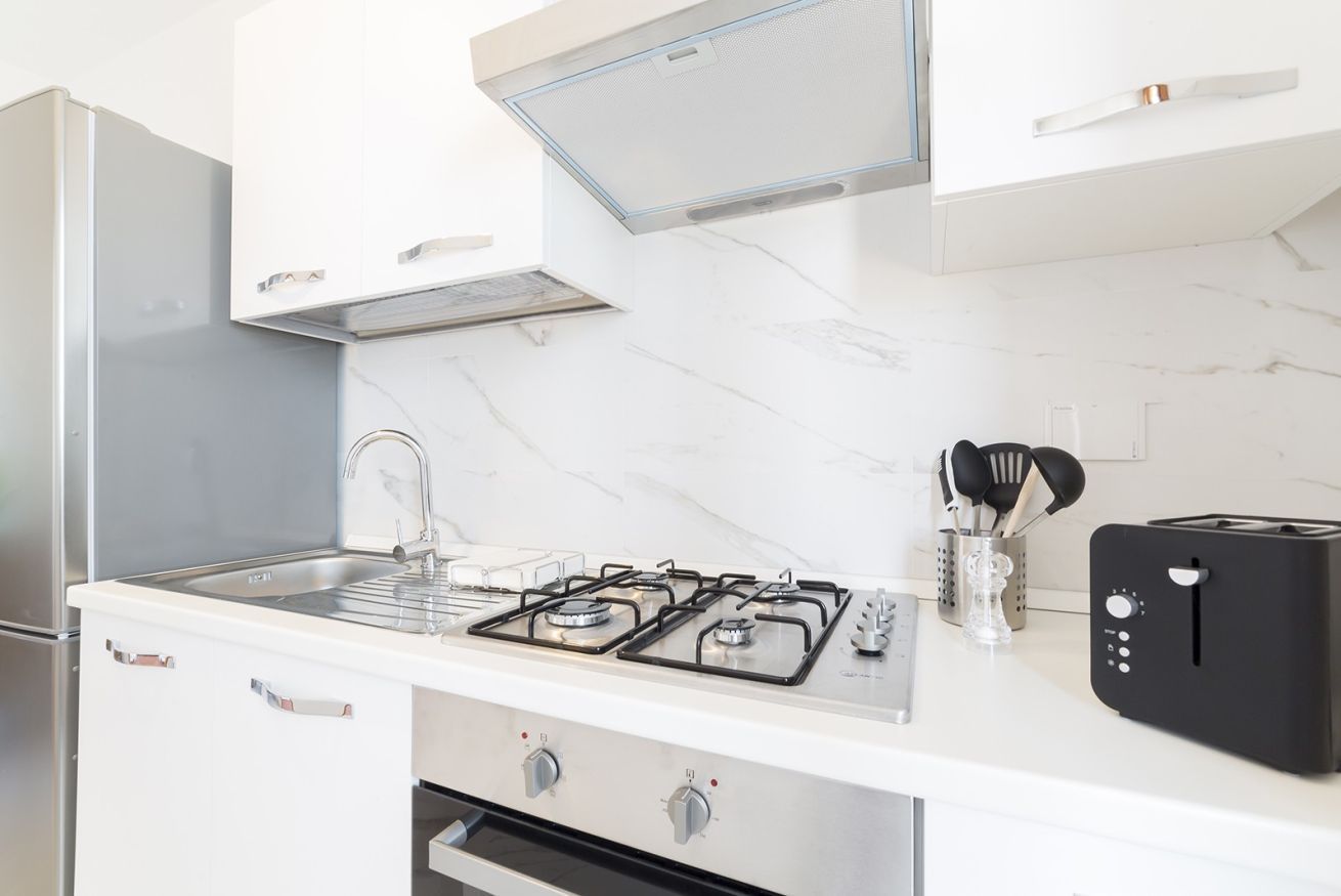Una cucina con fornello a gas, lavello, tostapane e frigorifero.