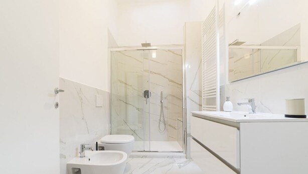 A modern bathroom with a glass-enclosed shower, a bidet, a sink, and a mirror. - A delightful split level apartment with a beautiful terrace with view on the hills. (Firenze)