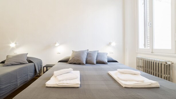 A hotel room with a bed, two bedside tables, and a window. - A delightful split level apartment with a beautiful terrace with view on the hills. (Firenze)