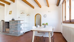 A dining area with a stone fireplace, white walls, and a wooden ceiling. - A delightful split level apartment with a beautiful terrace with view on the hills. (Firenze)