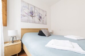 A bedroom with a bed, pillows, a nightstand with a lamp, and a wall-mounted abstract painting. - Large apartment for 6 adults close to the Santa Maria Novella Church and the central rail station. (Firenze)