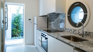 A modern kitchen with a built-in oven, a sink, and a window with a view of a tree.