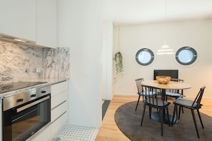 A modern kitchen with white cabinets, a marble countertop, and a built-in oven.