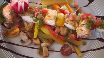 Une assiette de nourriture comprenant divers légumes et un morceau de poisson, le tout agrémenté d’herbes aromatiques.