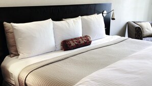 A neatly made bed with white linens, a quilted blanket, and a patterned throw pillow. - Hôtel Restaurant - Les Jardins du Lac (Autun)