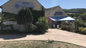 A building with a sign indicating it is a hotel and a restaurant. There is a parking sign pointing to the left. - Hôtel Restaurant - Les Jardins du Lac (Autun)