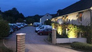 A hotel with a paved driveway, parked cars, and a building with ivy. - Hôtel Restaurant - Les Jardins du Lac (Autun)