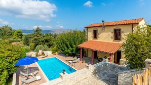 Une maison à deux étages dotée d’une piscine, d’un espace salon extérieur et offrant une vue sur la campagne.