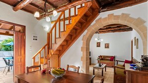 Un escalier en bois mène à un espace repas où une table est dressée pour deux personnes, entourée de chaises.