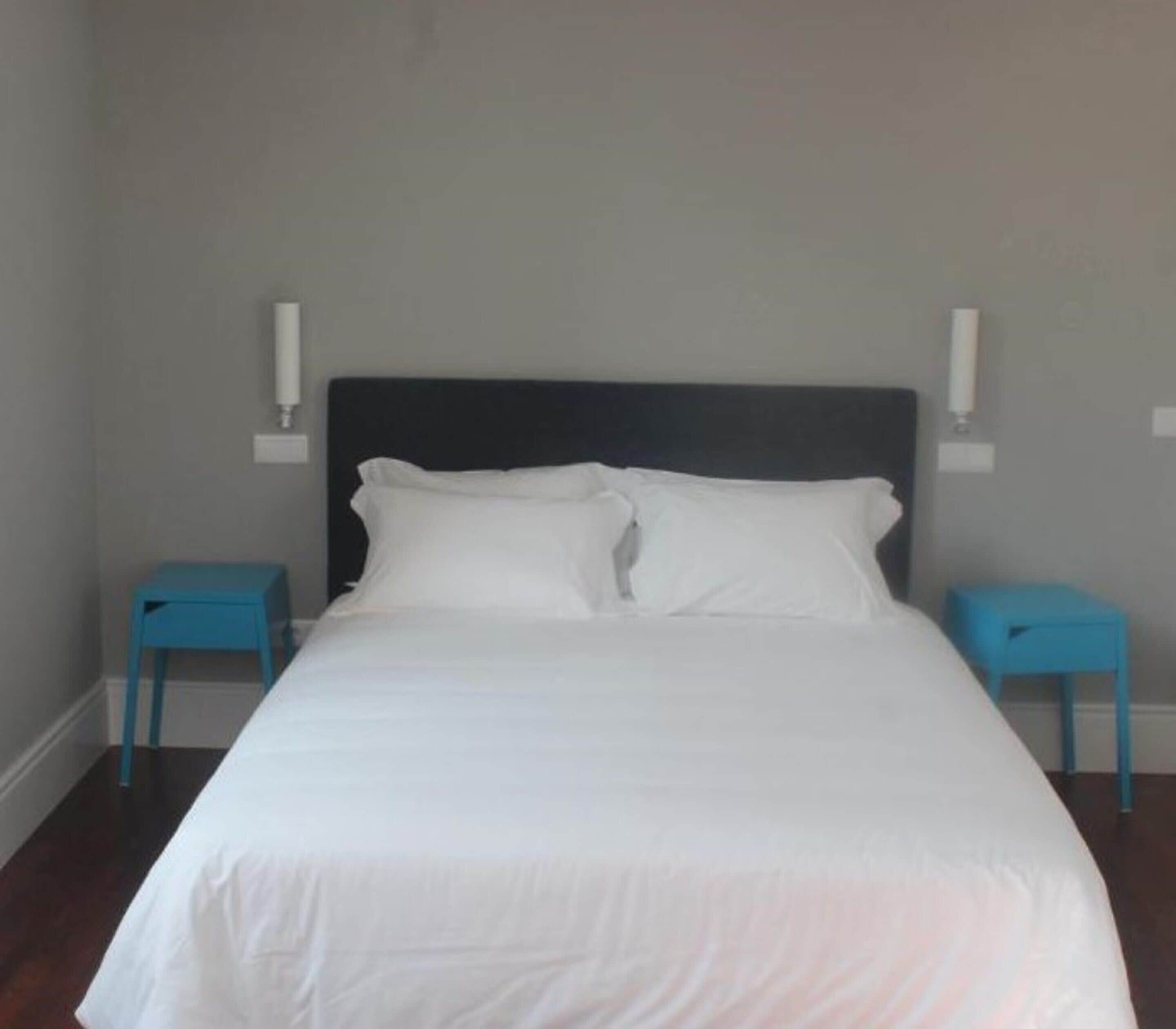 Une chambre à coucher avec un lit, deux tables de chevet et une tête de lit.