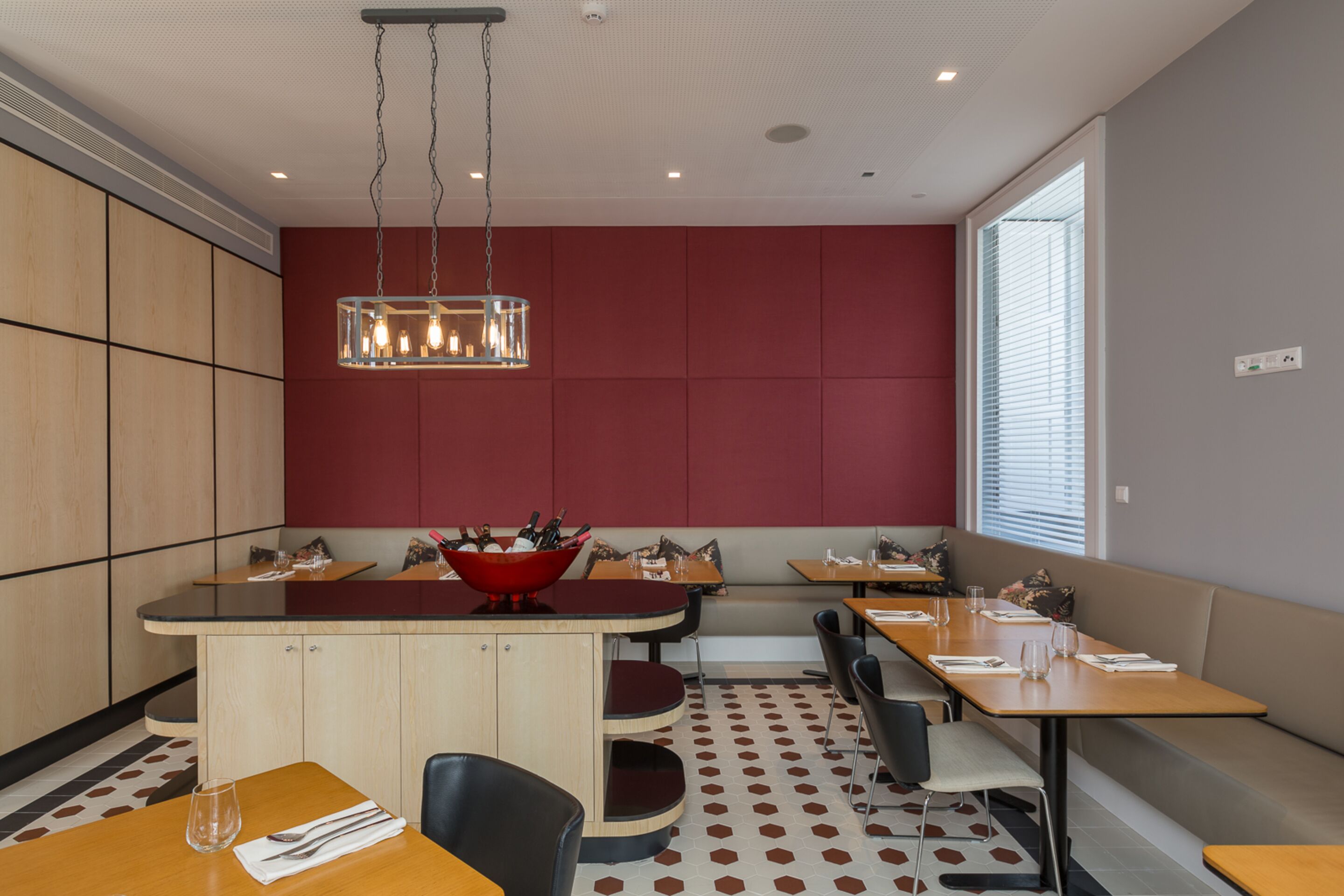 A modern dining area with a central island, seating arrangements, and a large window providing natural light.