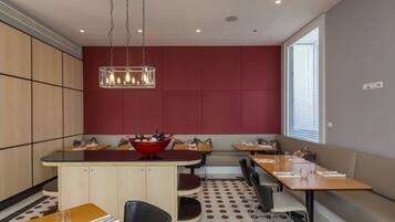 A modern dining area with a central island, seating arrangements, and a large window providing natural light.