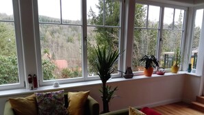 Quarto com uma grande janela, um sofá, uma cadeira e um vaso de planta.