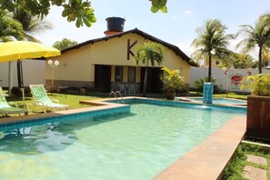Una piscina con sillas de descanso y un edificio con una gran 'K' en la fachada.