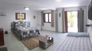 A bedroom with a bed, a coffee table, a TV, and a window with curtains. - Paracuru Kitefriends Pousada (Paracuru)