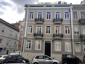 Um edifício de vários andares com fachada estampada, várias varandas e uma entrada central.