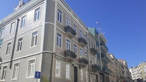 A multi-story residential building with a patterned facade, balconies, and a clear blue sky.