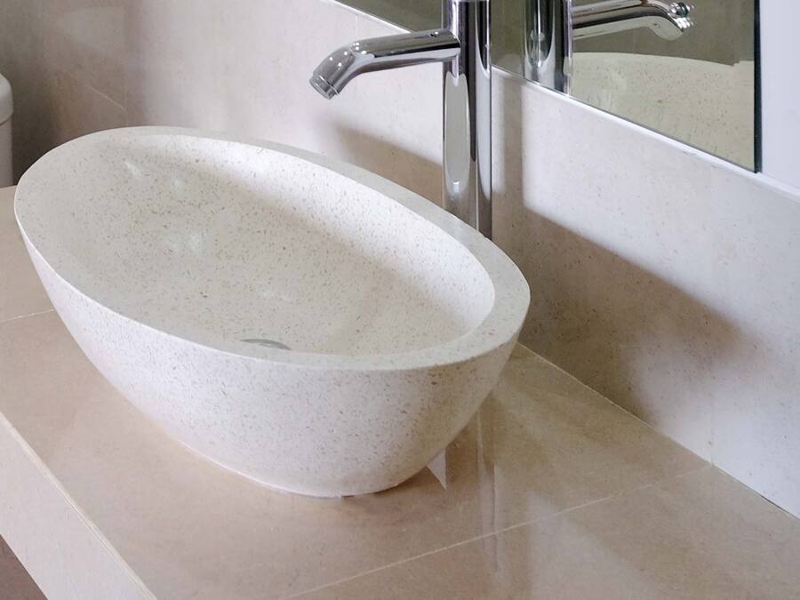A bathroom with a white toilet, a white sink with a speckled design, and a toilet paper holder.
