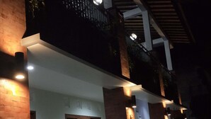 A modern house with a brick facade, a balcony with railings, and multiple light fixtures. - Bale Delod Guest House (Ubud)