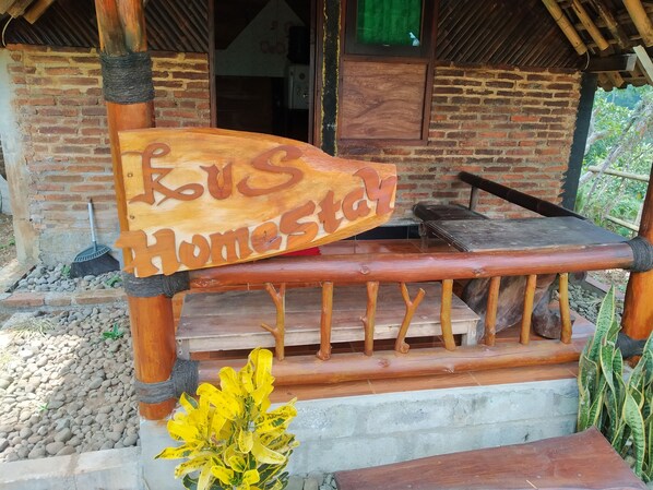A wooden bench with a sign reading "KVS Homestay" in front of a brick building.