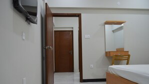 Quarto com cama e cómoda de madeira, e um espelho.