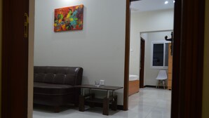 Uma sala de estar com um sofá de couro marrom escuro, uma mesa de centro de madeira e um quadro abstrato colorido na parede.