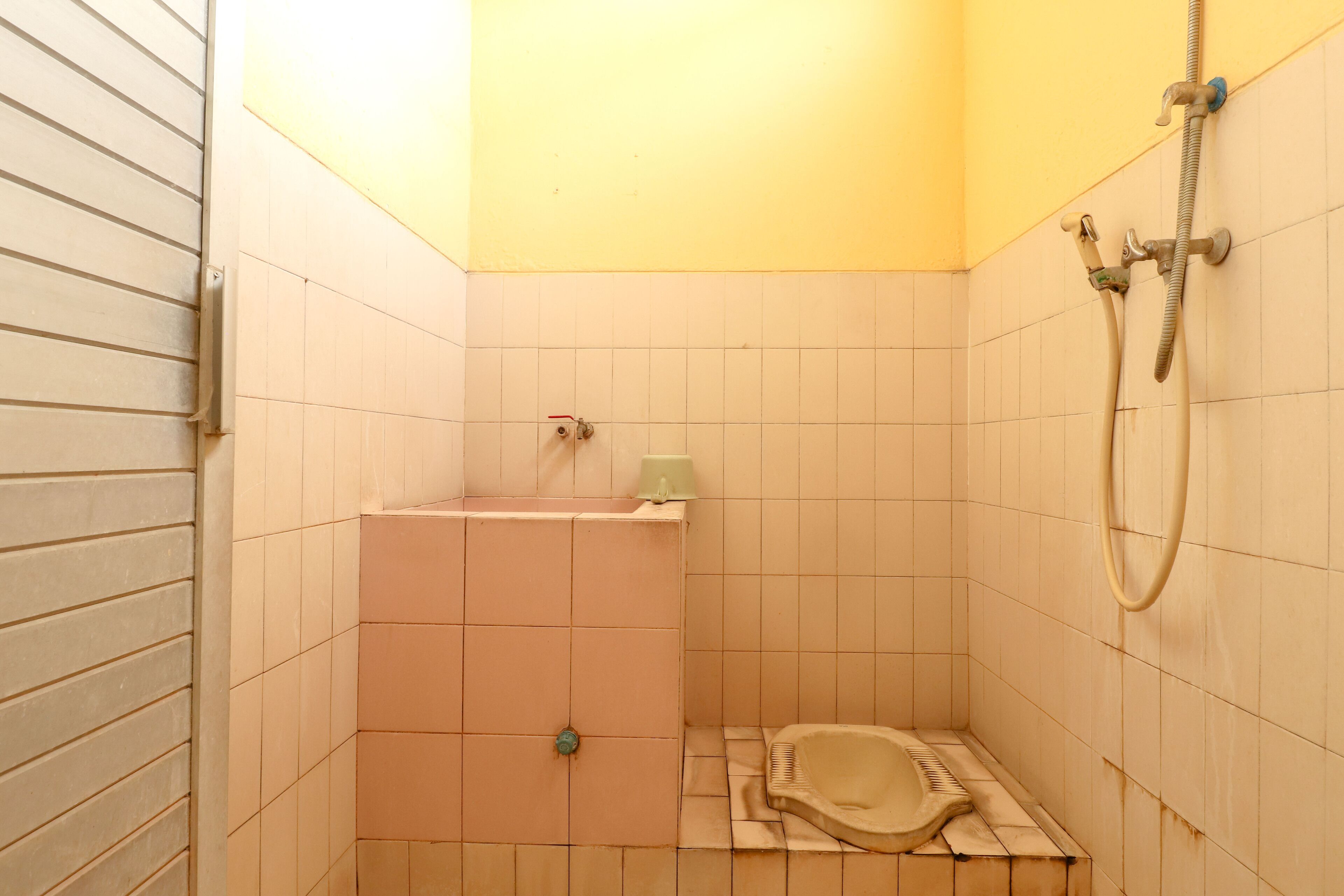 A small, tiled bathroom with a shower, a toilet, and a sink.