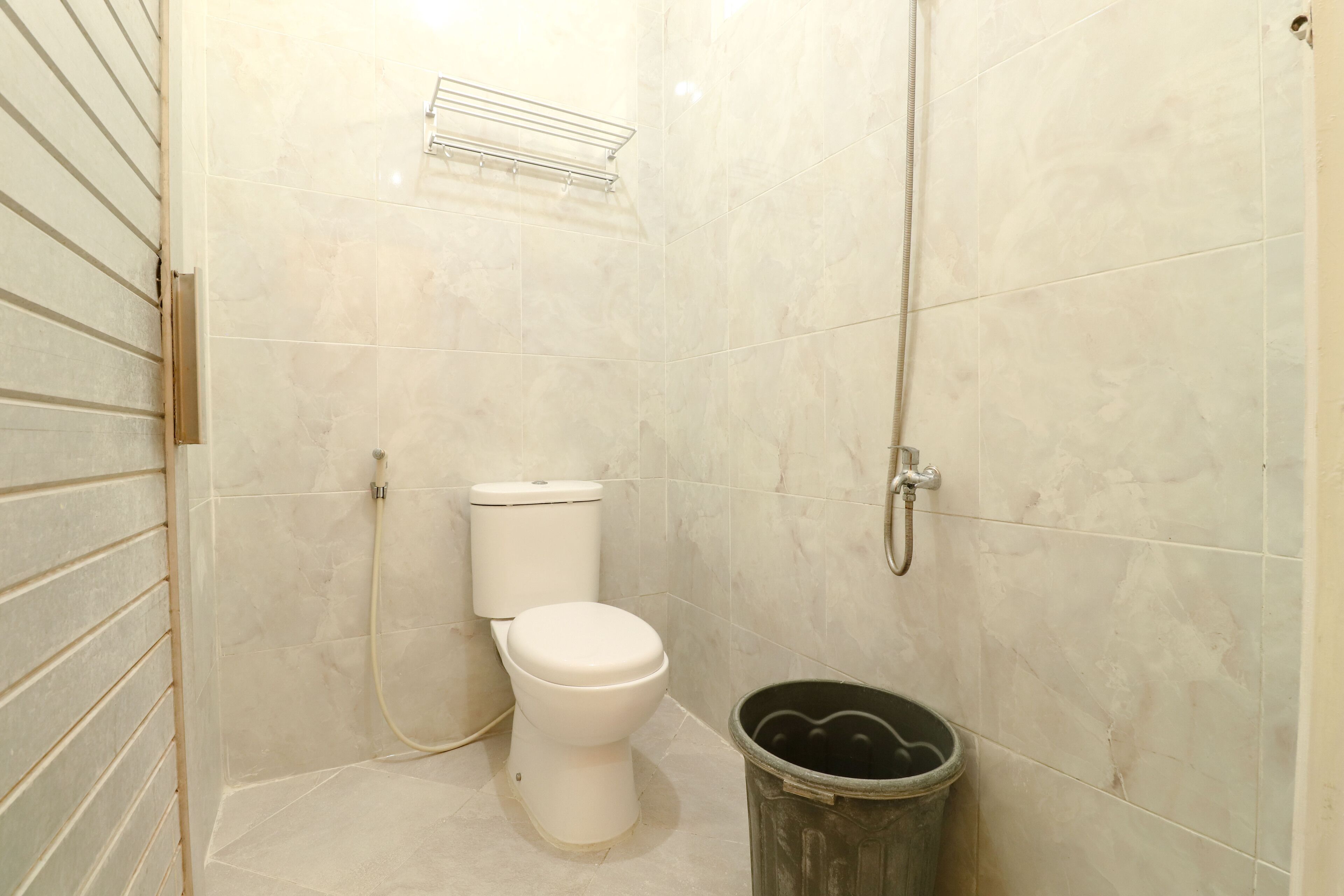 A small, clean bathroom with a toilet, a shower, and a trash can.