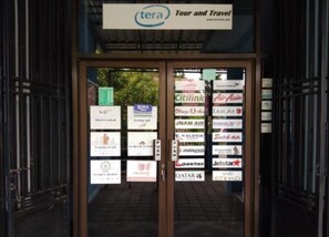 A glass door entrance with multiple airline and hotel logos displayed on the glass. - Ijen Osing Homestay (Banyuwangi)