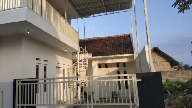 Um edifício moderno com fachada branca, uma varanda e uma escadaria que leva a um andar superior.