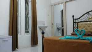 Quarto de hotel com cama, guarda-roupa, janela com cortinas, mesa de cabeceira e espelho.