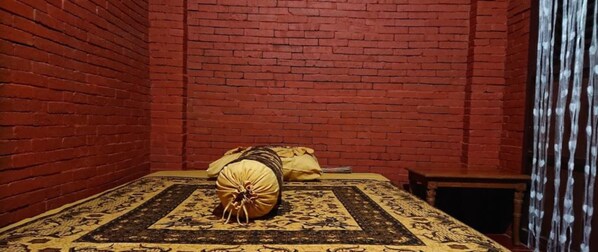 Cozy retreat with a brick wall, comfortable bed, and a bench for relaxation.