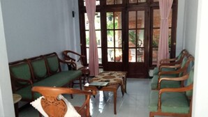A room with wooden furniture, including a sofa and chairs, and a table. - Majapahit Homestay by Bhagaskara (Bejijong)