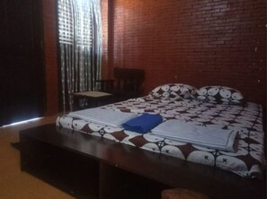 Cozy retreat with a comfortable bed, nightstand, and window with vertical blinds.