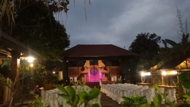 An outdoor venue with a stage, rows of chairs, and a backdrop. - Majapahit Homestay by Bhagaskara (Bejijong)