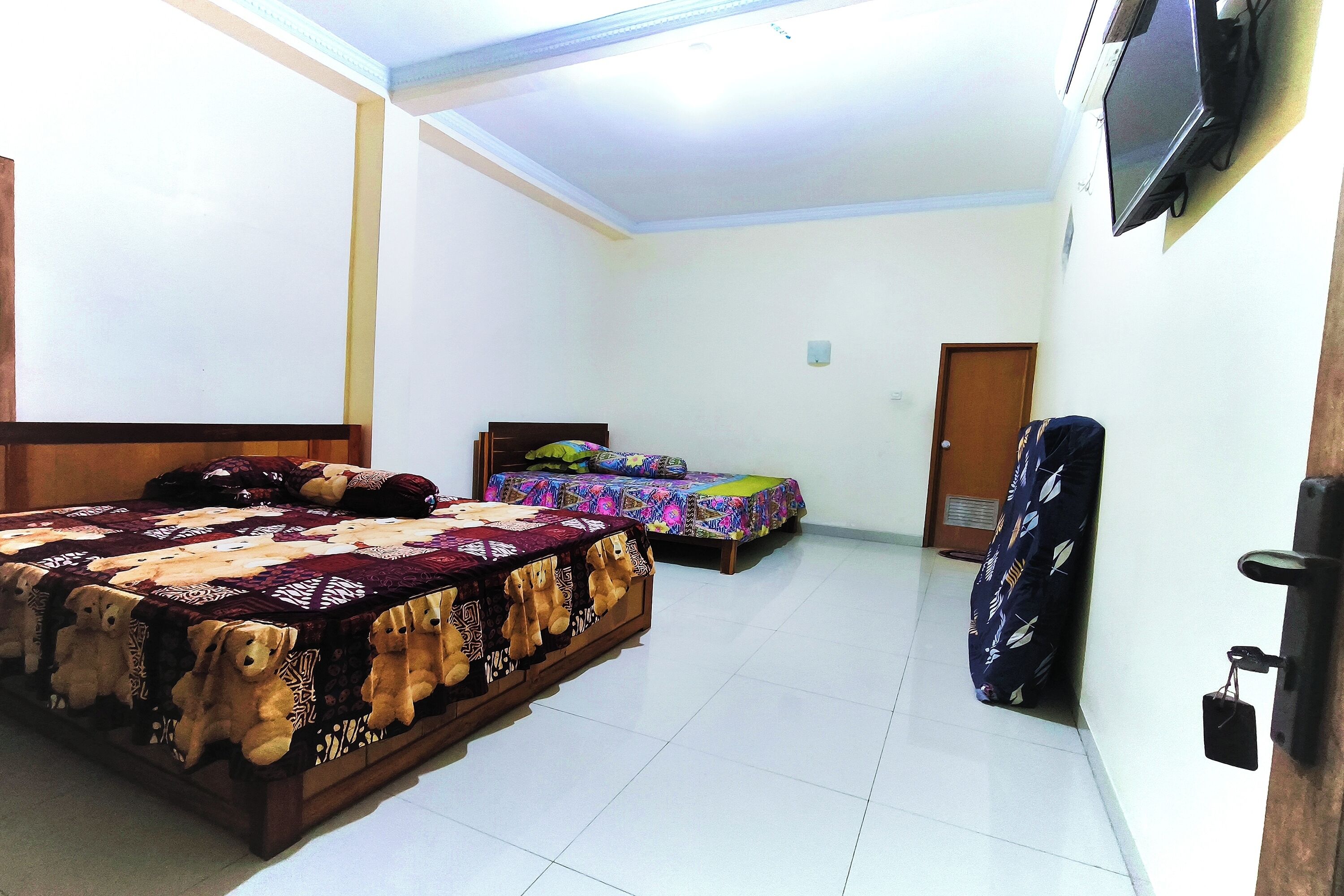 A room with two beds, a television, and a door.