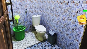 Un baño pequeño con un inodoro, un cubo verde y un cubo de basura.