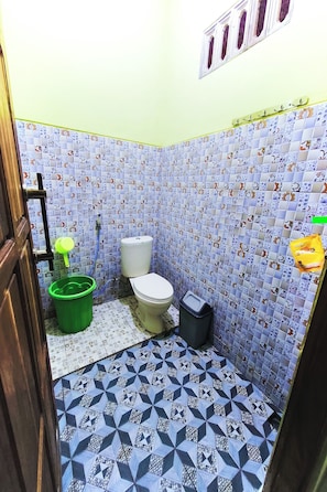Um banheiro pequeno com vaso sanitário, um balde verde e uma lixeira.