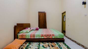 Un dormitorio con una cama, cabecera de madera, colcha estampada y una alfombra colorida.