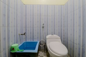 Un baño con inodoro, una bañera azul y un cubo de basura verde.