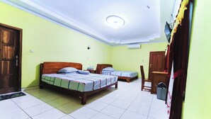 Una habitación con dos camas, un escritorio, una silla, una puerta y un equipo de aire acondicionado.