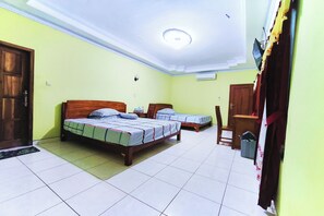Una habitación con dos camas, un escritorio, una silla, una puerta y un equipo de aire acondicionado.
