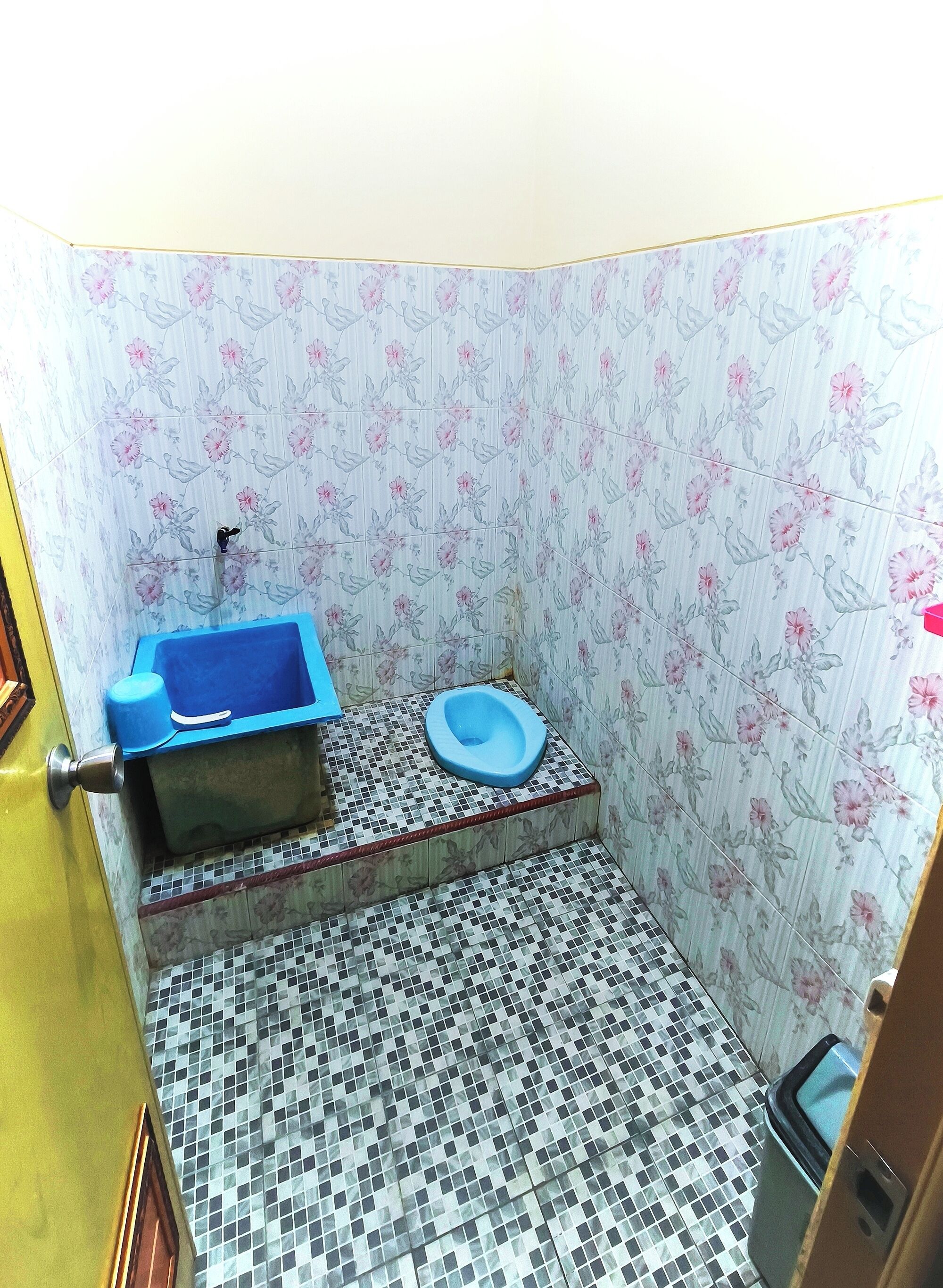 A small bathroom with a blue toilet, a blue basin, and a tiled floor.